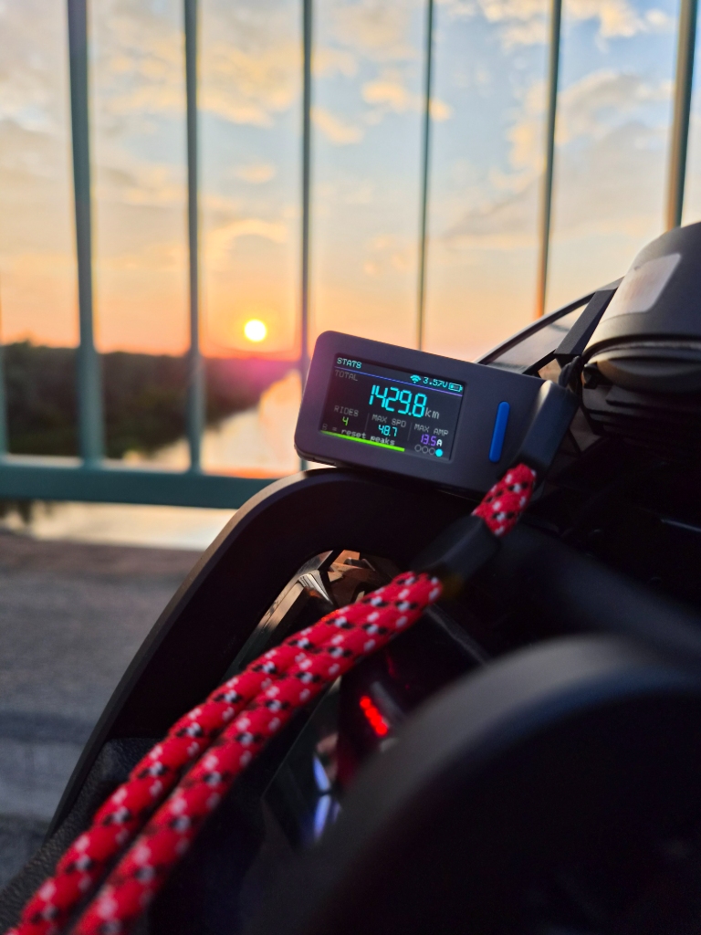 EucBuddy device on a railing at sunset, showing 1429.8 km total distance